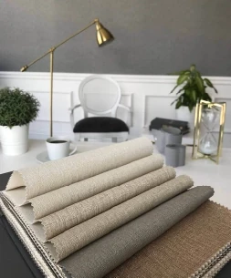 Tekstil tabanlı duvar kağıdı numuneleri — keten dokulu, bej ve gri tonlarında rulolar